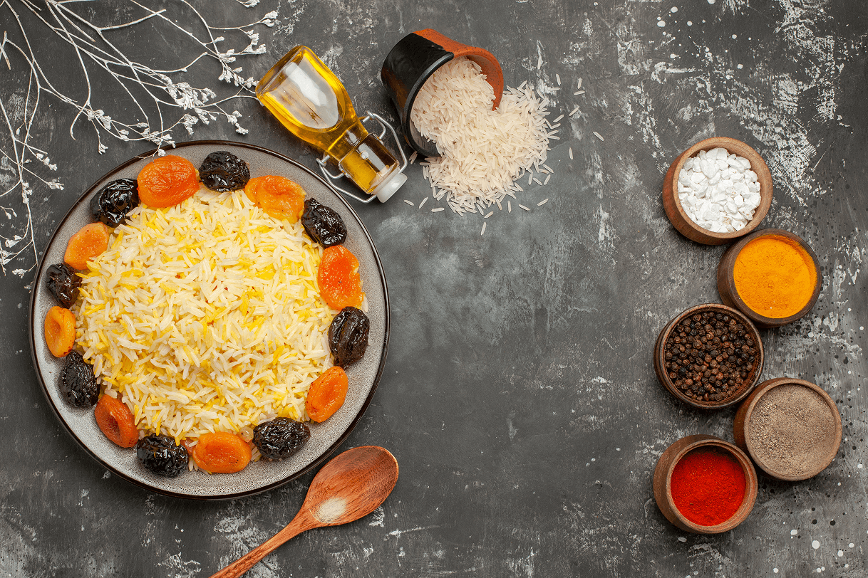 top-close-up-view-rice-spoon-bottle-oil-plate-rice-with-dried-fruits-bowls-spices-rice